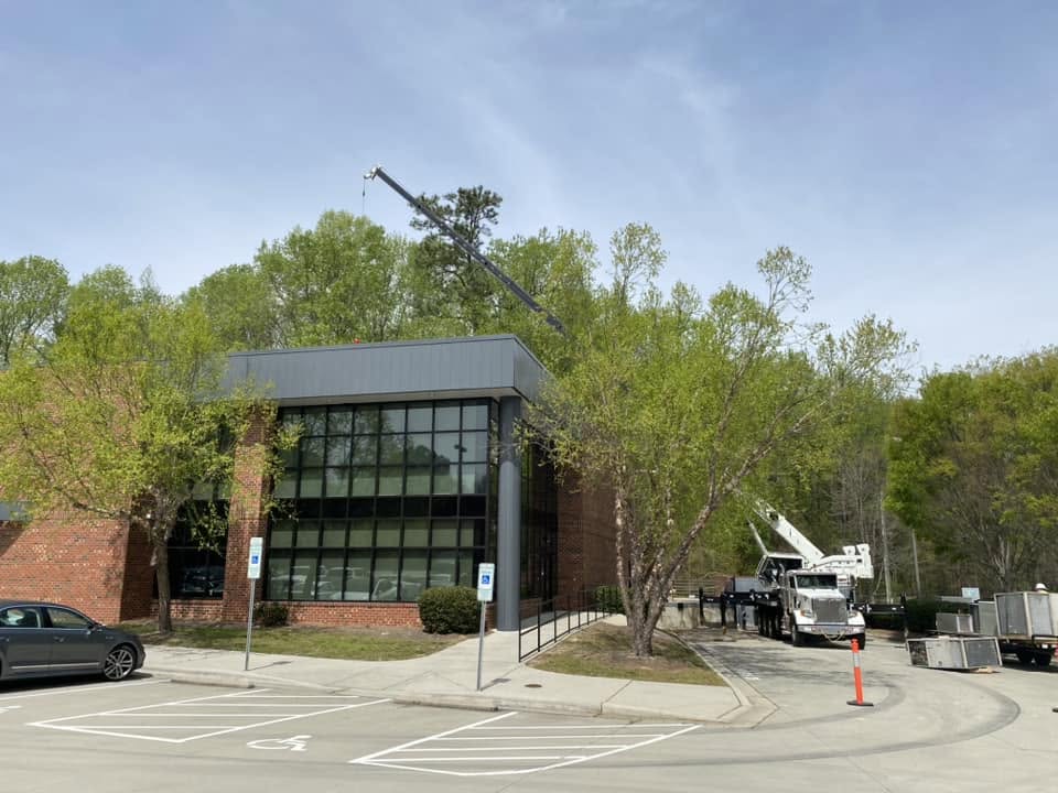 setting hvac unit on office building roof with a crane