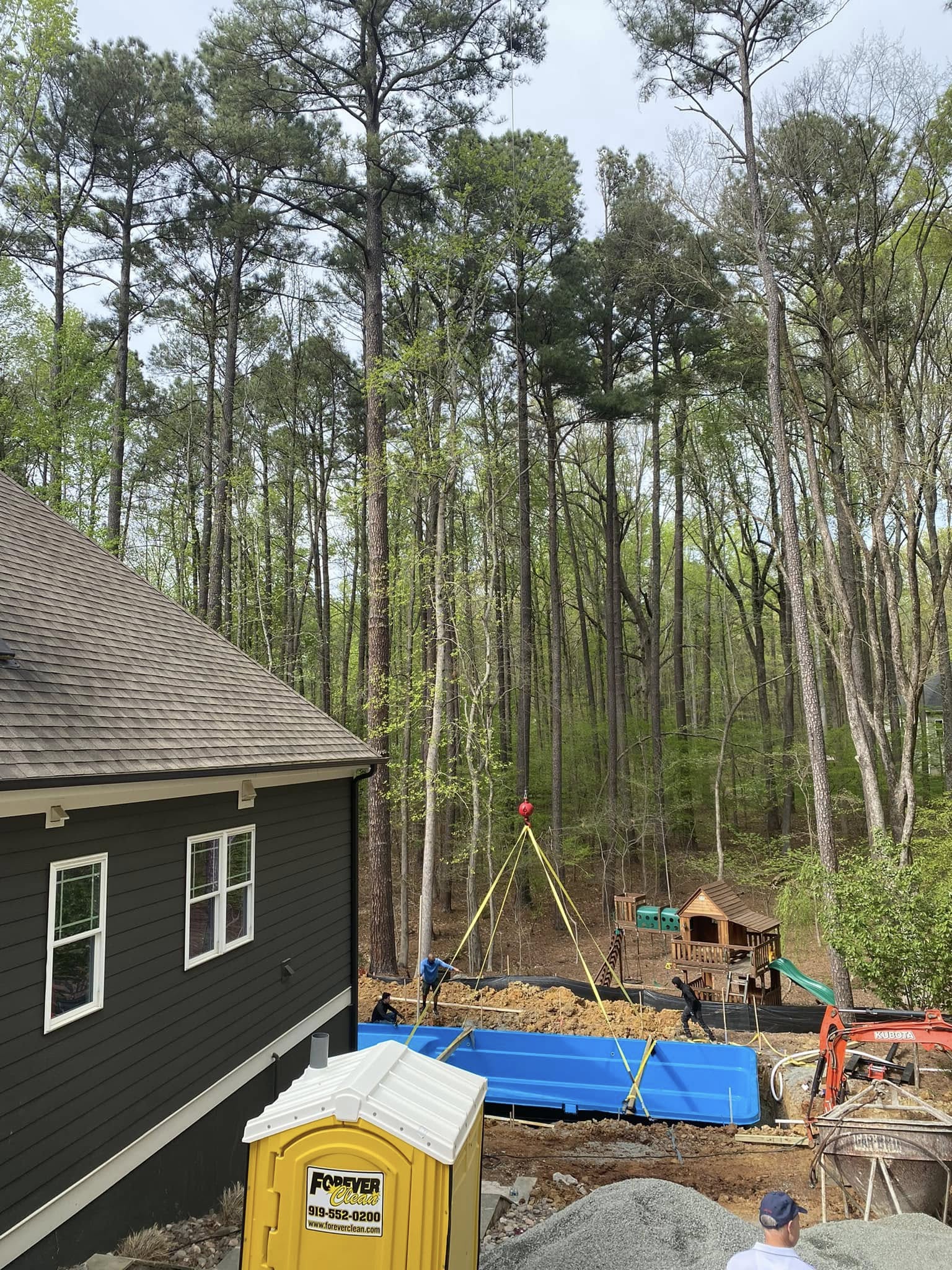setting pool in residential backyard with crane